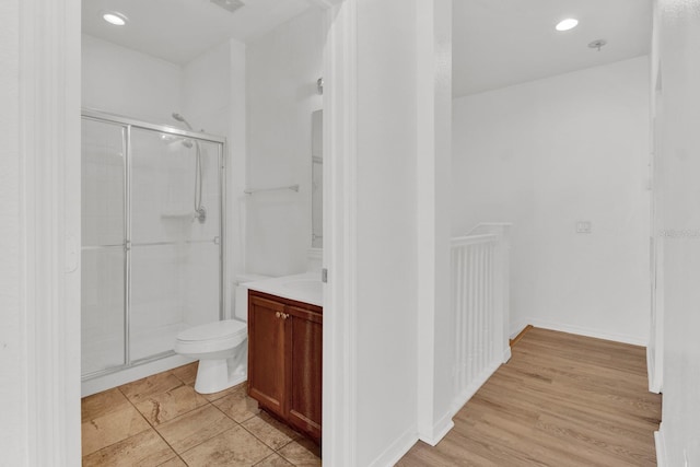 bathroom featuring a shower with door, vanity, wood-type flooring, and toilet