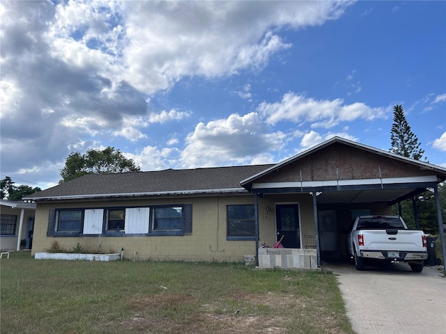 single story home featuring concrete driveway, an attached carport, a front yard, and concrete block siding