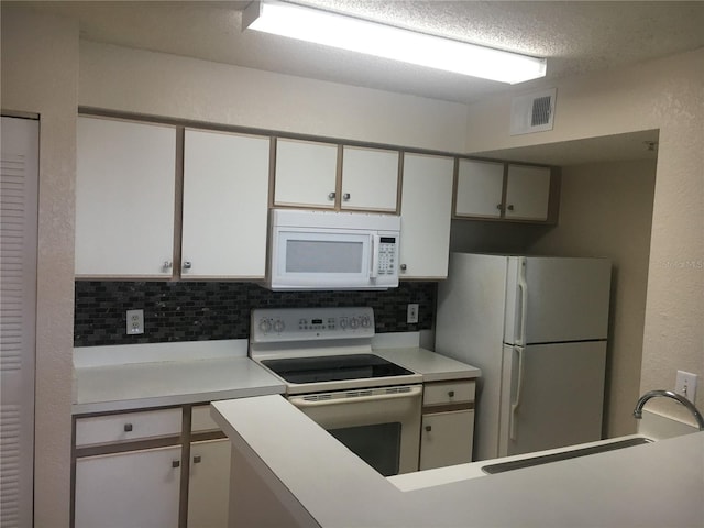 kitchen with white appliances, backsplash, and white cabinetry