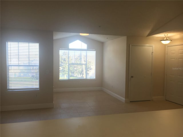 tiled empty room with vaulted ceiling