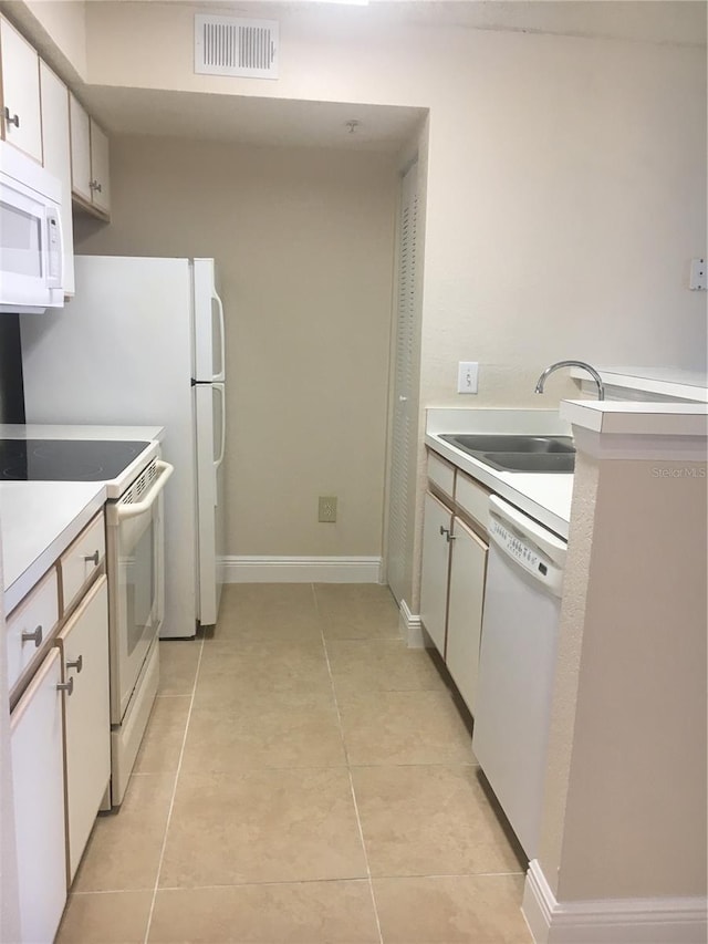 kitchen with white cabinetry, light tile patterned floors, white appliances, and sink