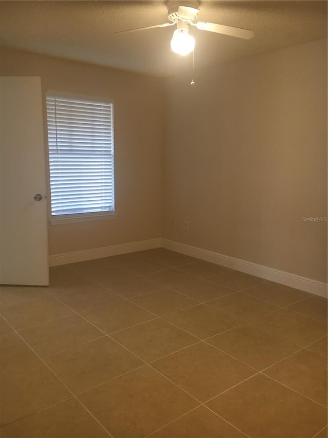 tiled empty room with ceiling fan and a textured ceiling