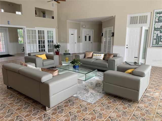 living room with ceiling fan, ornamental molding, and a towering ceiling