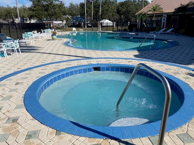 view of swimming pool featuring a hot tub and a patio area