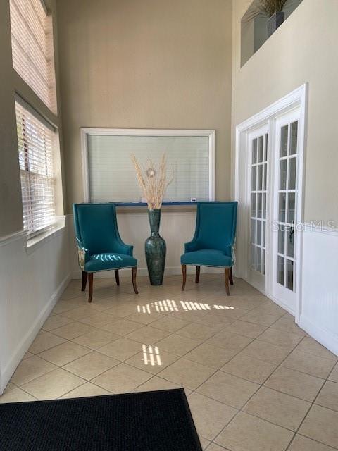 living area with a high ceiling, light tile patterned floors, and french doors