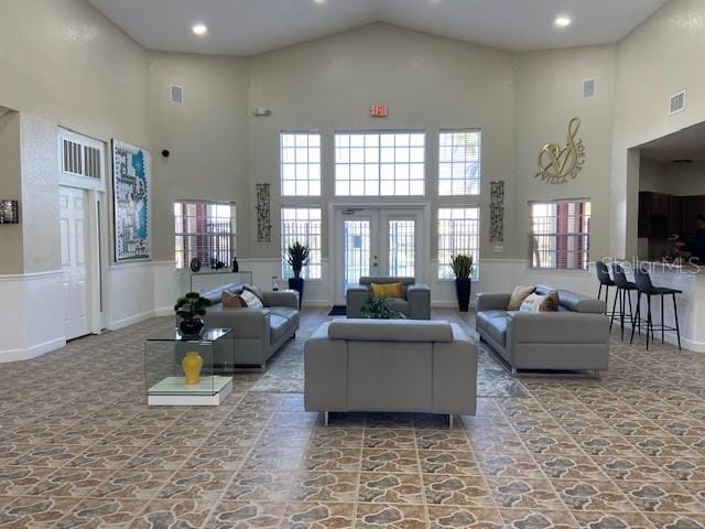 carpeted living room with french doors and high vaulted ceiling