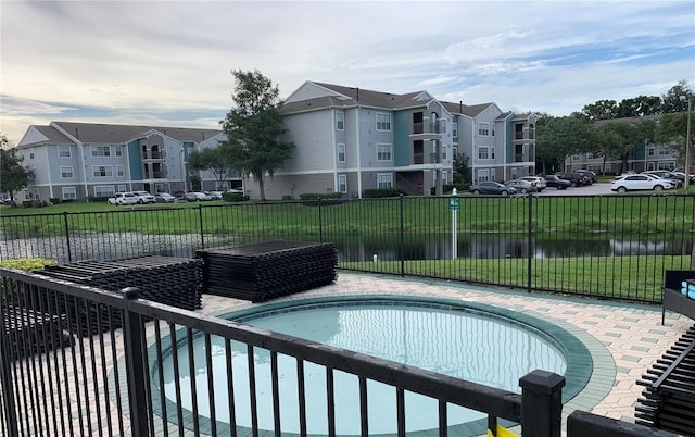 view of pool featuring a water view and a lawn