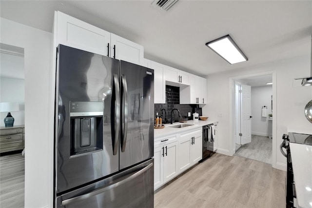 kitchen featuring light hardwood / wood-style flooring, white cabinetry, sink, black appliances, and tasteful backsplash