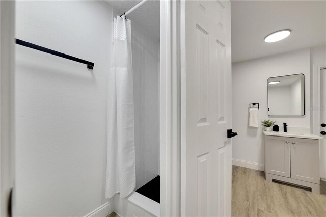 bathroom with a shower with shower curtain, hardwood / wood-style flooring, and vanity