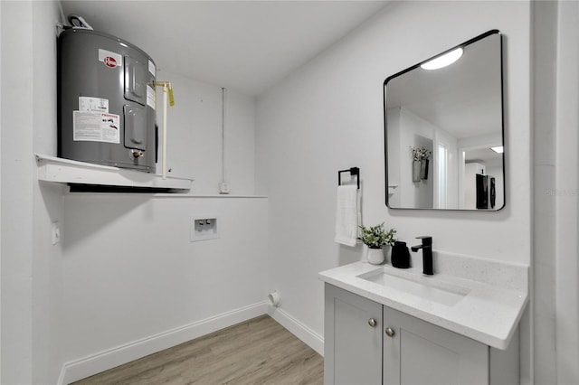 clothes washing area featuring cabinets, washer hookup, water heater, sink, and light wood-type flooring