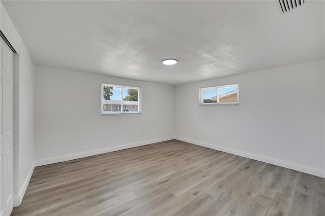 unfurnished room featuring a textured ceiling and light hardwood / wood-style floors