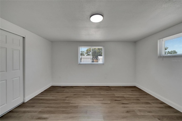 empty room with wood-type flooring and a textured ceiling