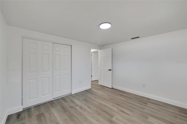 unfurnished bedroom with light hardwood / wood-style flooring and a closet