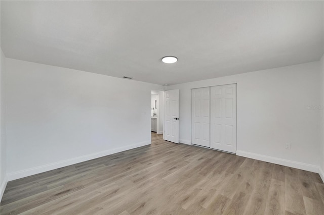 unfurnished bedroom featuring light wood-type flooring and a closet