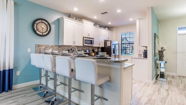 kitchen featuring white cabinetry, light stone counters, and stainless steel appliances