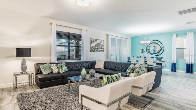 living room with a healthy amount of sunlight, a chandelier, and light hardwood / wood-style floors