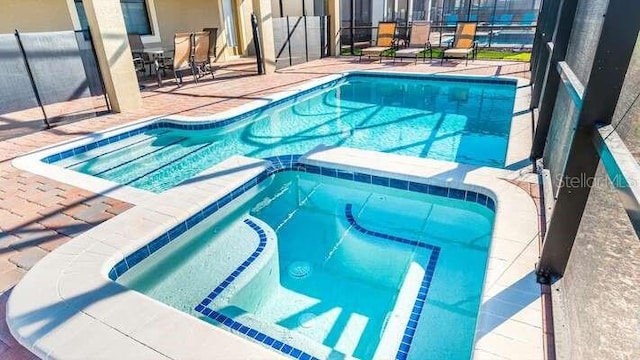 view of swimming pool featuring an in ground hot tub and a patio area