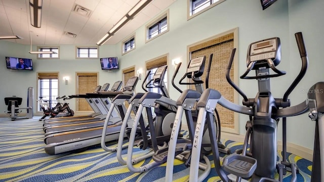 exercise room with a towering ceiling and carpet