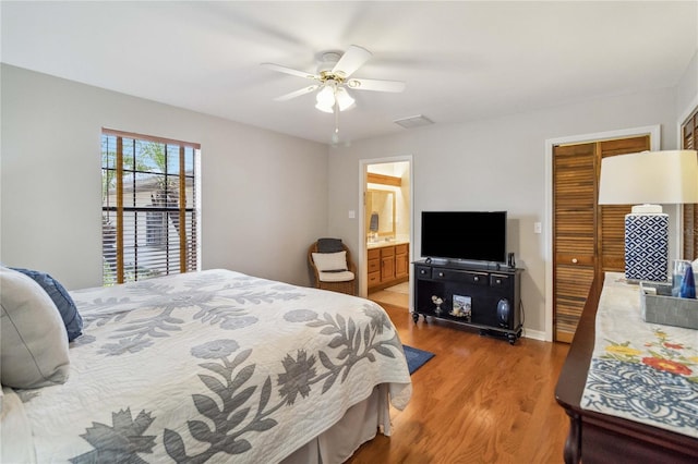 bedroom with a closet, ceiling fan, hardwood / wood-style floors, and ensuite bath