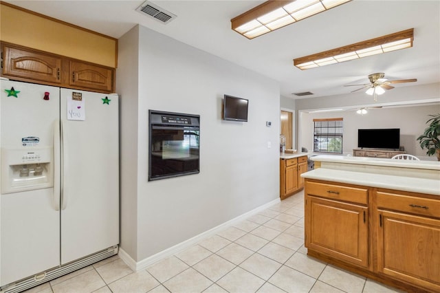 kitchen featuring light tile patterned flooring, ceiling fan, white fridge with ice dispenser, and black oven