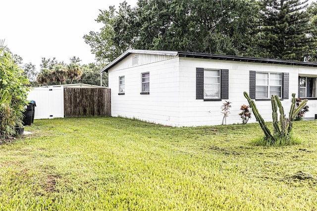 view of property exterior with a lawn and a storage unit