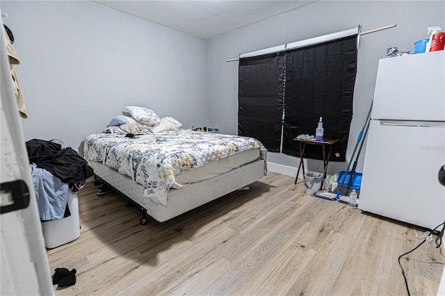 bedroom featuring white refrigerator and light hardwood / wood-style flooring