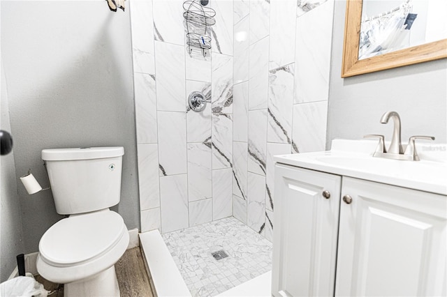 bathroom with vanity, toilet, and a tile shower