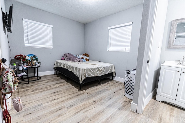 bedroom with light hardwood / wood-style floors and a textured ceiling