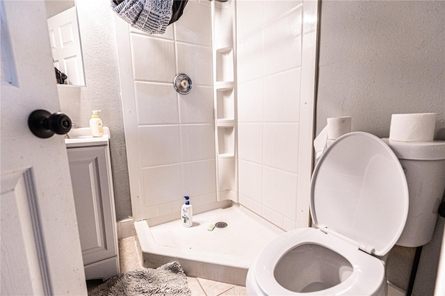 bathroom featuring tiled shower, toilet, and tile patterned flooring