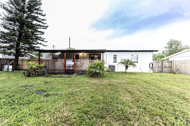 back of property with a yard and central AC unit