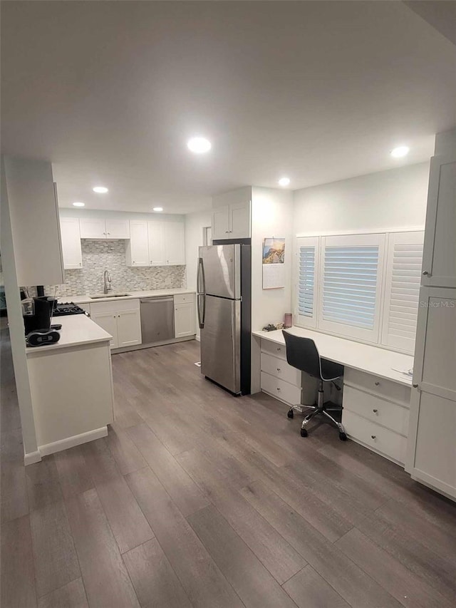 kitchen with dark hardwood / wood-style flooring, backsplash, stainless steel appliances, sink, and white cabinets