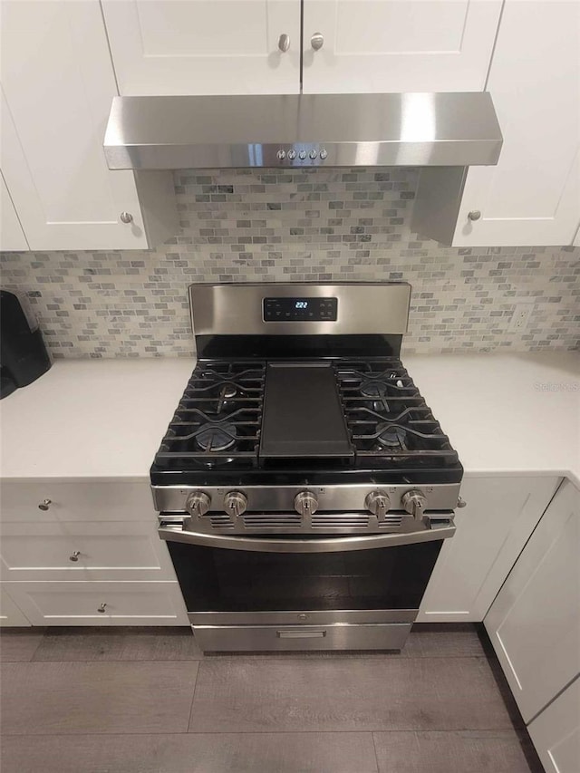 kitchen featuring white cabinetry, backsplash, wall chimney exhaust hood, and stainless steel gas range oven