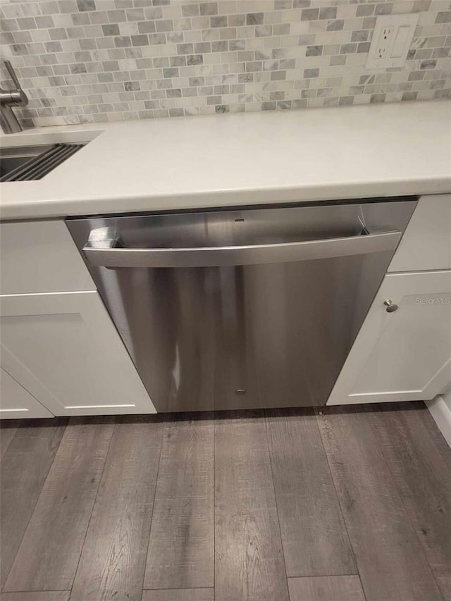 interior details featuring stainless steel dishwasher, tasteful backsplash, and dark wood-type flooring