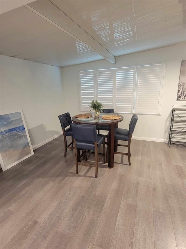 dining room featuring wood-type flooring and beamed ceiling