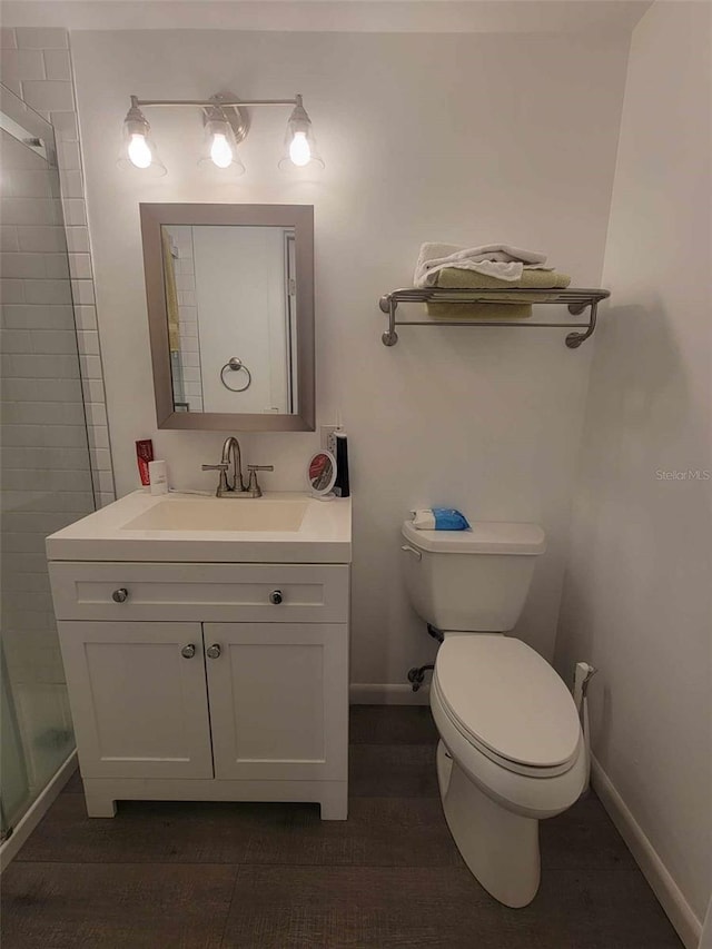 bathroom featuring a shower with shower door, toilet, and vanity