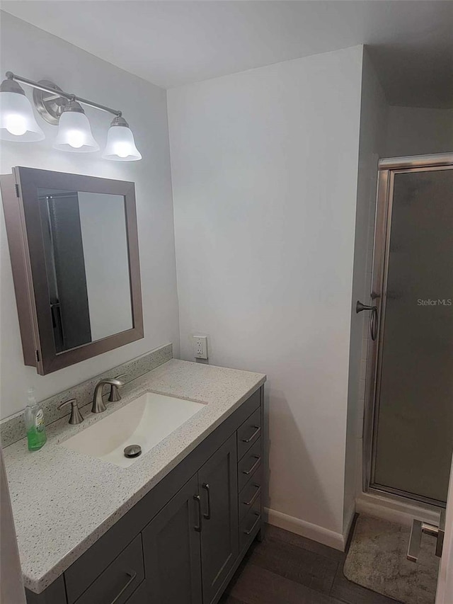 bathroom with a shower with shower door and vanity