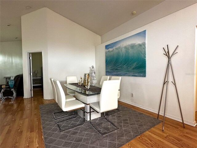 dining area featuring lofted ceiling and dark hardwood / wood-style flooring