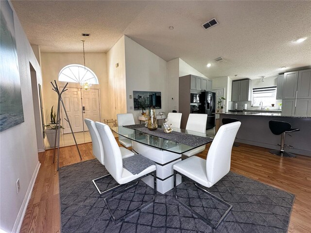 dining area with a textured ceiling, vaulted ceiling, and dark hardwood / wood-style flooring