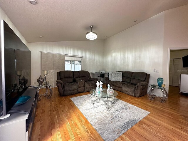 living room with a textured ceiling, wood-type flooring, and vaulted ceiling