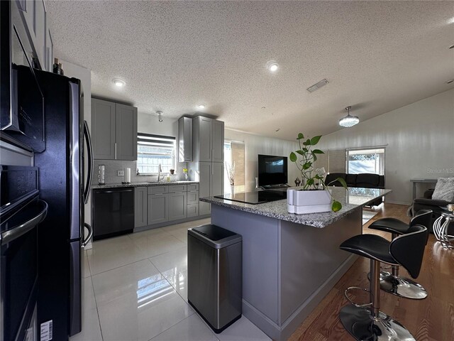 kitchen with gray cabinets, black appliances, and a textured ceiling