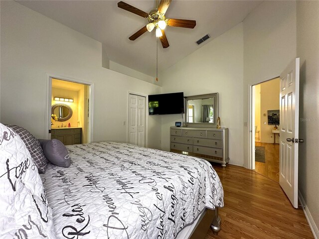 bedroom featuring ceiling fan, high vaulted ceiling, connected bathroom, wood-type flooring, and a closet