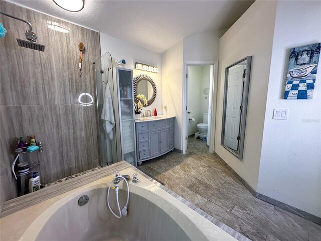 full bathroom featuring toilet, a textured ceiling, vanity, and independent shower and bath