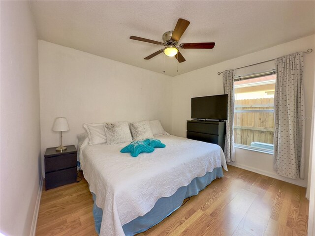 bedroom featuring a textured ceiling, light wood-type flooring, and ceiling fan