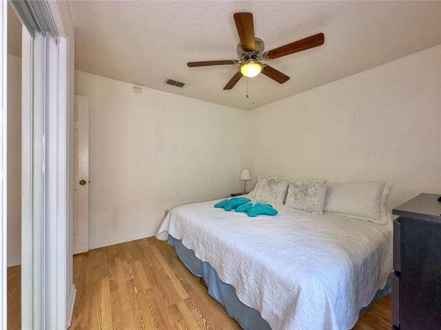 bedroom featuring light hardwood / wood-style flooring, a textured ceiling, and ceiling fan