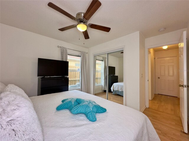 bedroom featuring a closet, light hardwood / wood-style floors, a textured ceiling, and ceiling fan