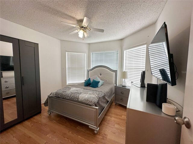 bedroom with ceiling fan, a textured ceiling, and light wood-type flooring