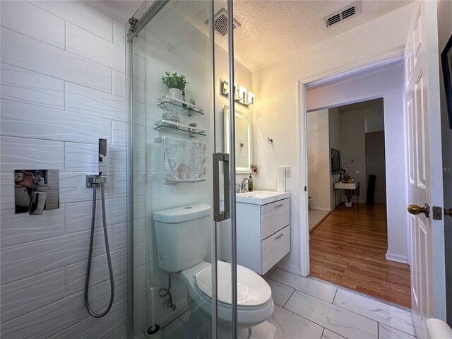 bathroom featuring toilet, a textured ceiling, vanity, and a shower