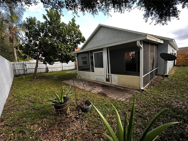 rear view of house with a patio, a sunroom, and a yard