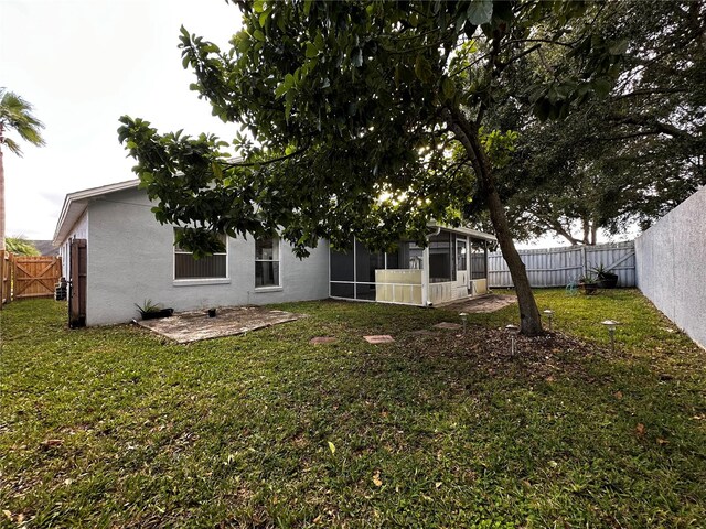 rear view of property featuring a sunroom and a lawn