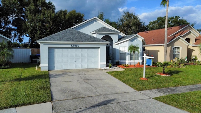 view of front of property featuring cooling unit, a garage, and a front lawn